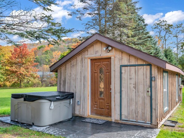 Una cabaña de madera con un jacuzzi y una puerta.