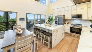 A spacious kitchen with a large island, white cabinetry, and a view of the outdoors.
