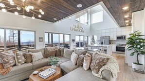 A spacious living area with a large sectional sofa, a wooden coffee table, and a view of the kitchen and dining area.