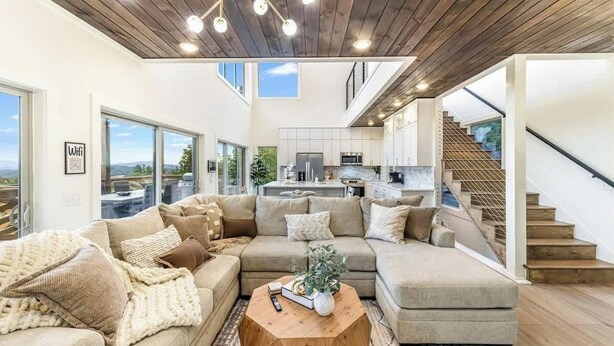 A modern living room with a sectional sofa, a round coffee table, and a staircase leading to an upper level.
