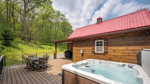 A wooden cabin with a hot tub and a deck with a table and chairs. - Charming Dog Friendly Retreat w/ Hot Tub (McHenry)