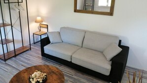 A living room with a sofa, a coffee table, a lamp, and a mirror on the wall.