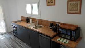 A compact kitchen with a wooden countertop, a sink, a coffee maker, a toaster, and a small refrigerator.