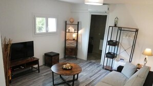 A living room with a sofa, coffee table, TV, and shelves.