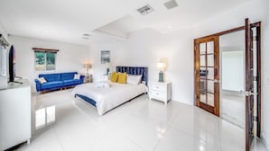Une chambre moderne avec un grand lit, un canapé bleu, une commode blanche et une porte en bois.