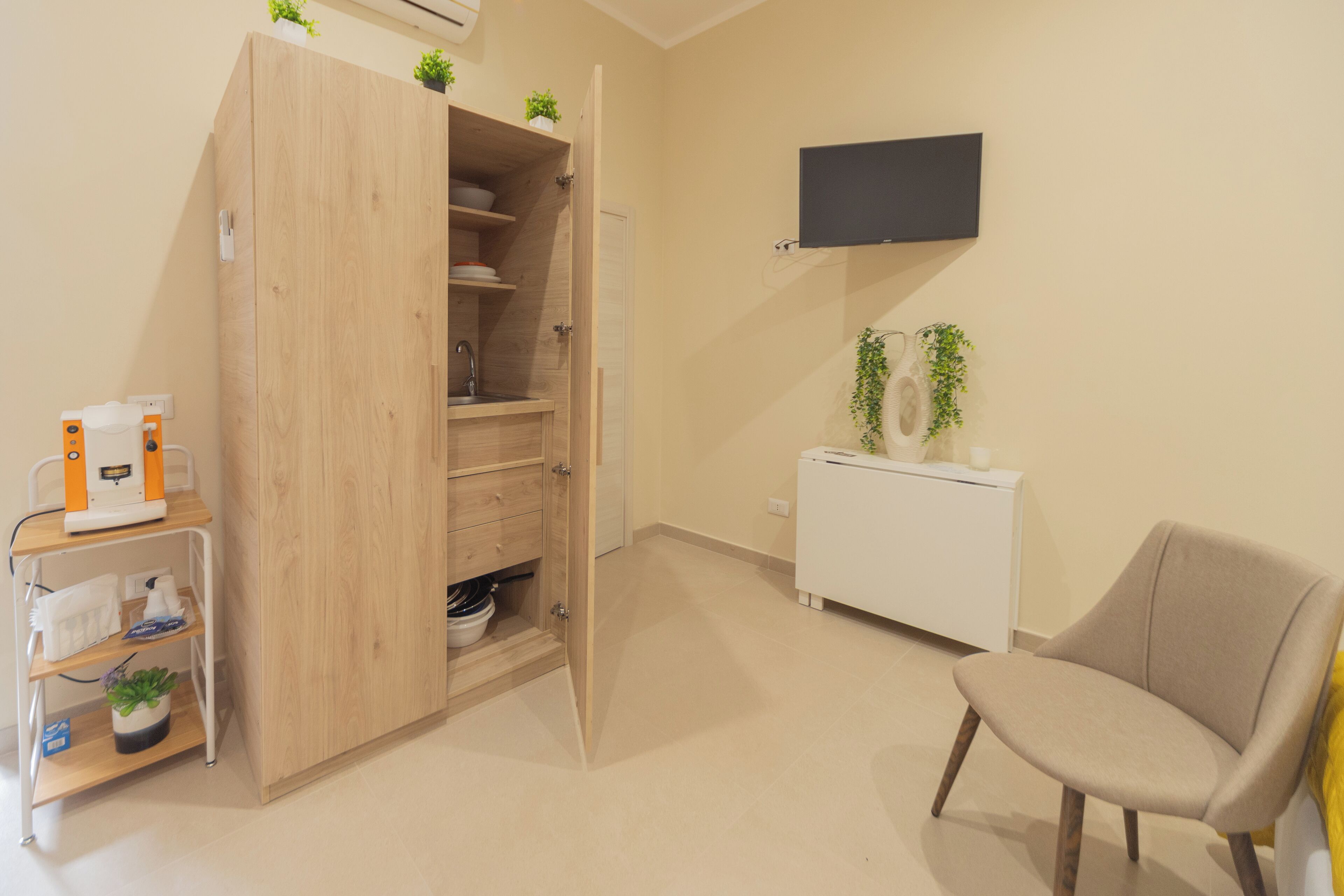 Ein Zimmer mit Holzschrank, weißem Heizkörper, Stuhl und Wand-Fernseher.