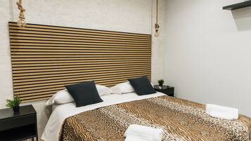 A modern hotel room with a striped headboard, a leopard print bedspread, and neatly folded towels on the bed.