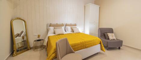 A bedroom with a bed, a chair, a cabinet, and a mirror.