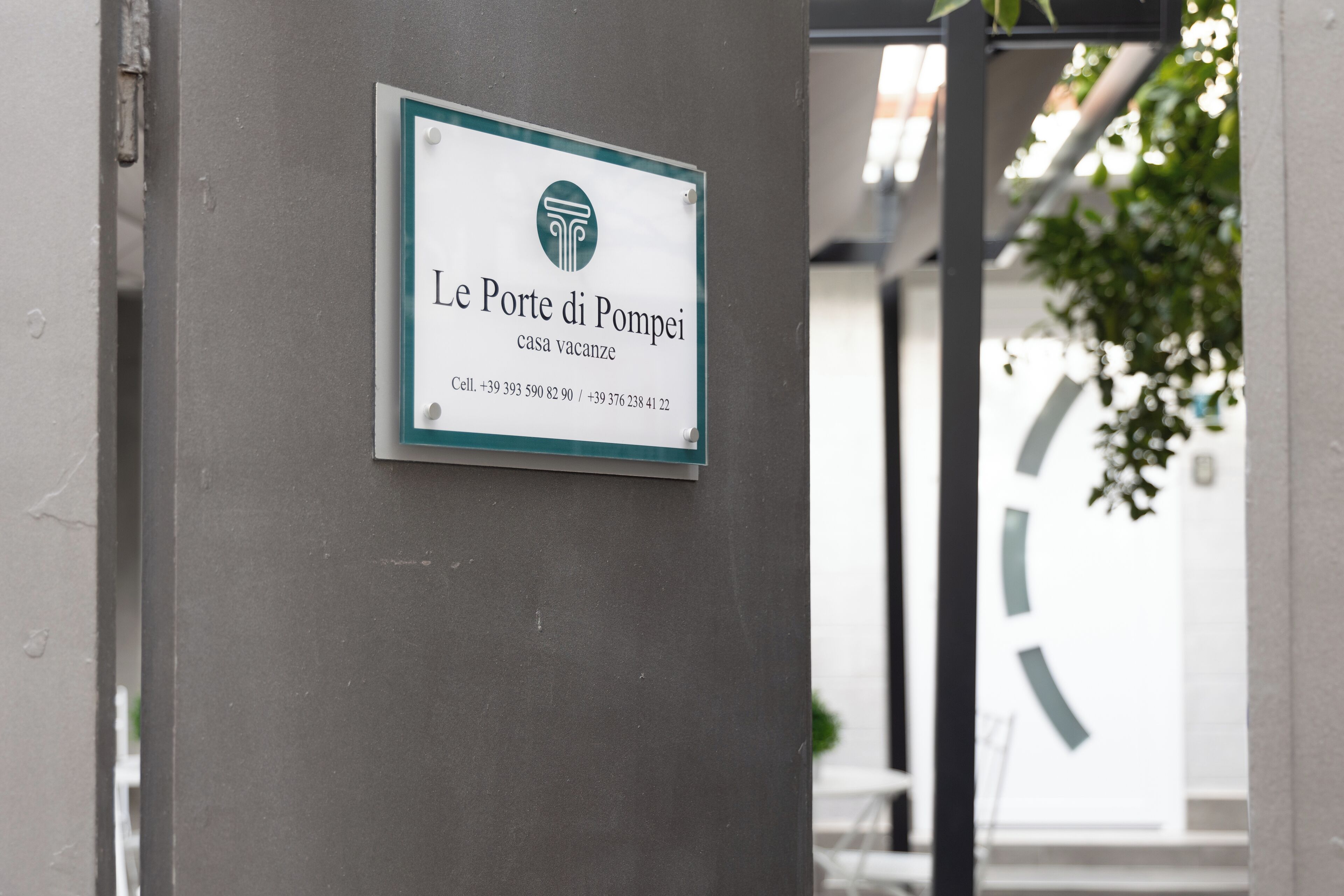 A sign for Le Porte di Pompei hotel with contact information.