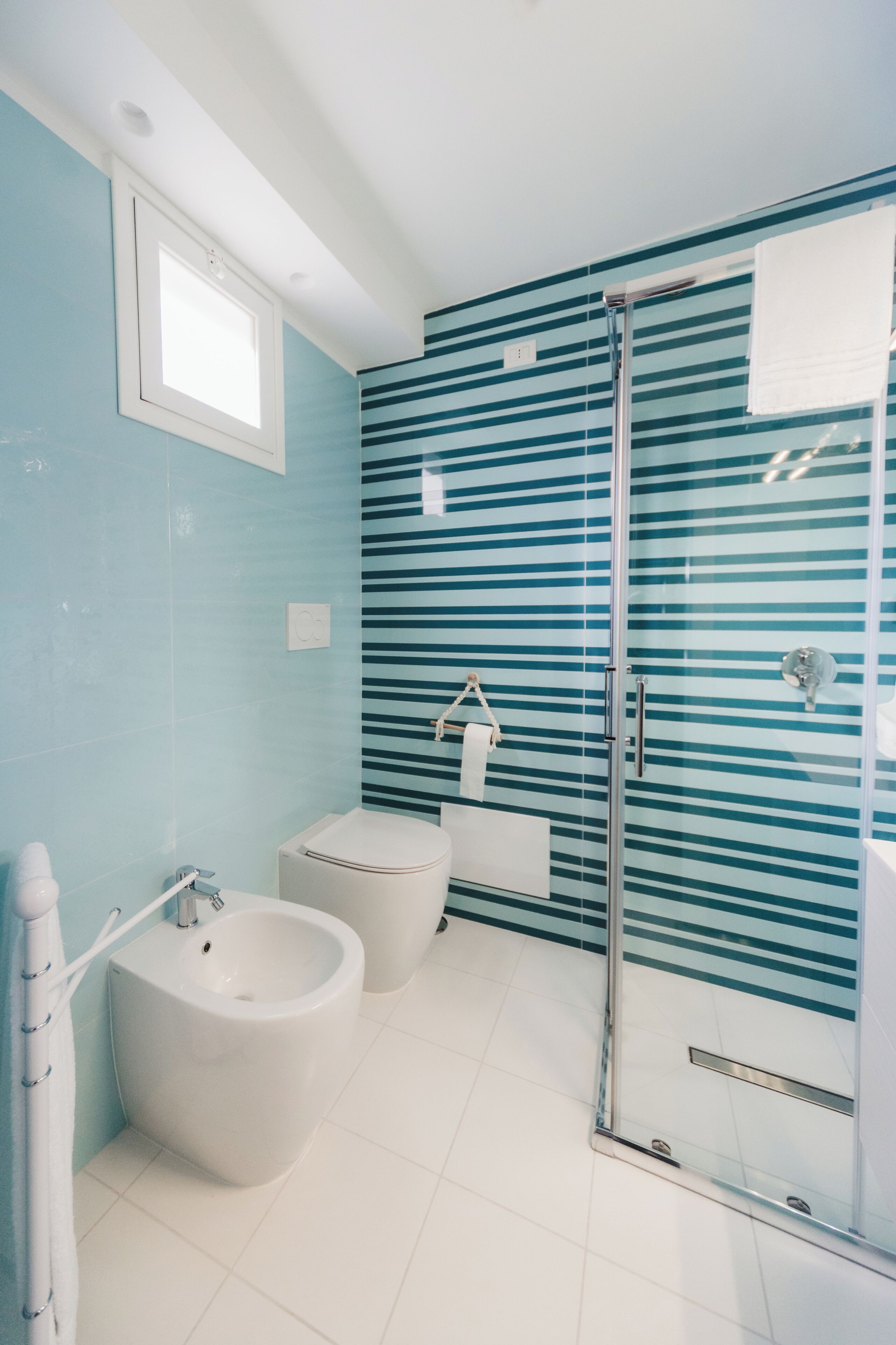 Ein modernes Badezimmer mit Duschkabine aus Glas, einem Bidet und einer Toilette.