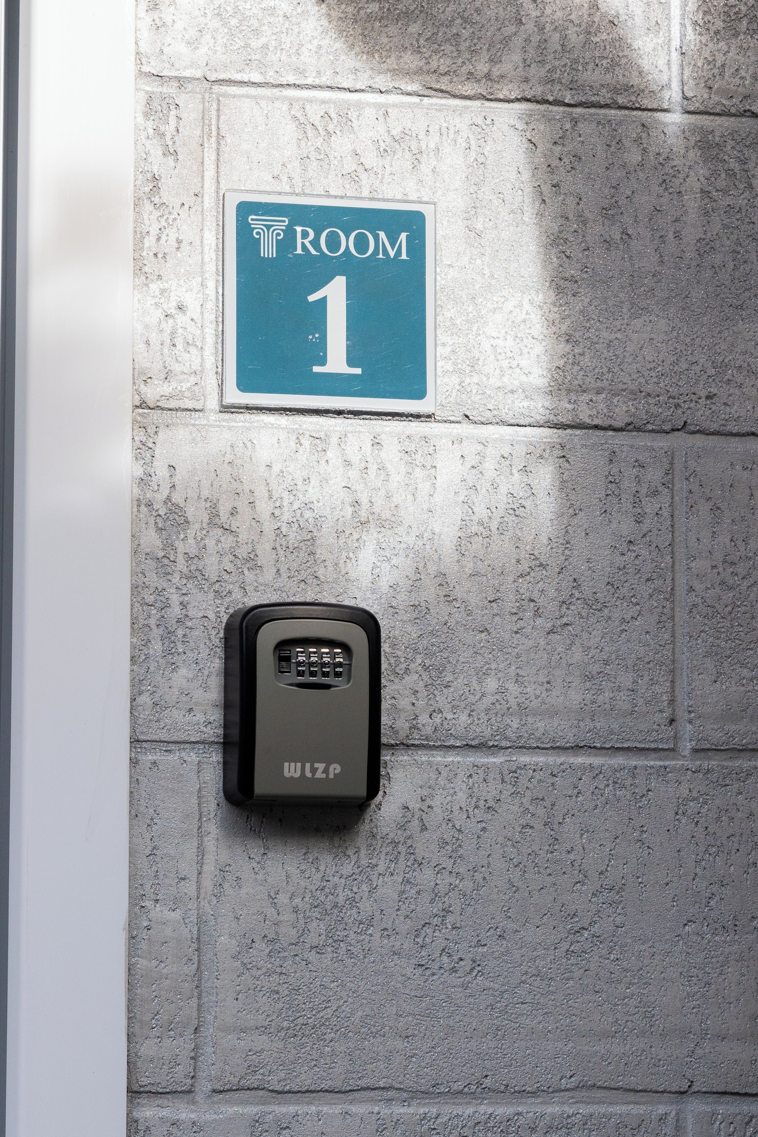 Un letrero en la pared que indica HABITACIÓN 1 con un teclado de seguridad debajo.