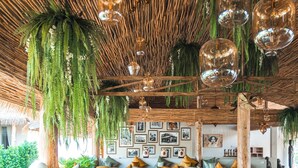 Un restaurant avec des tables et des chaises en bois, des lampes suspendues et un plafond en chaume.