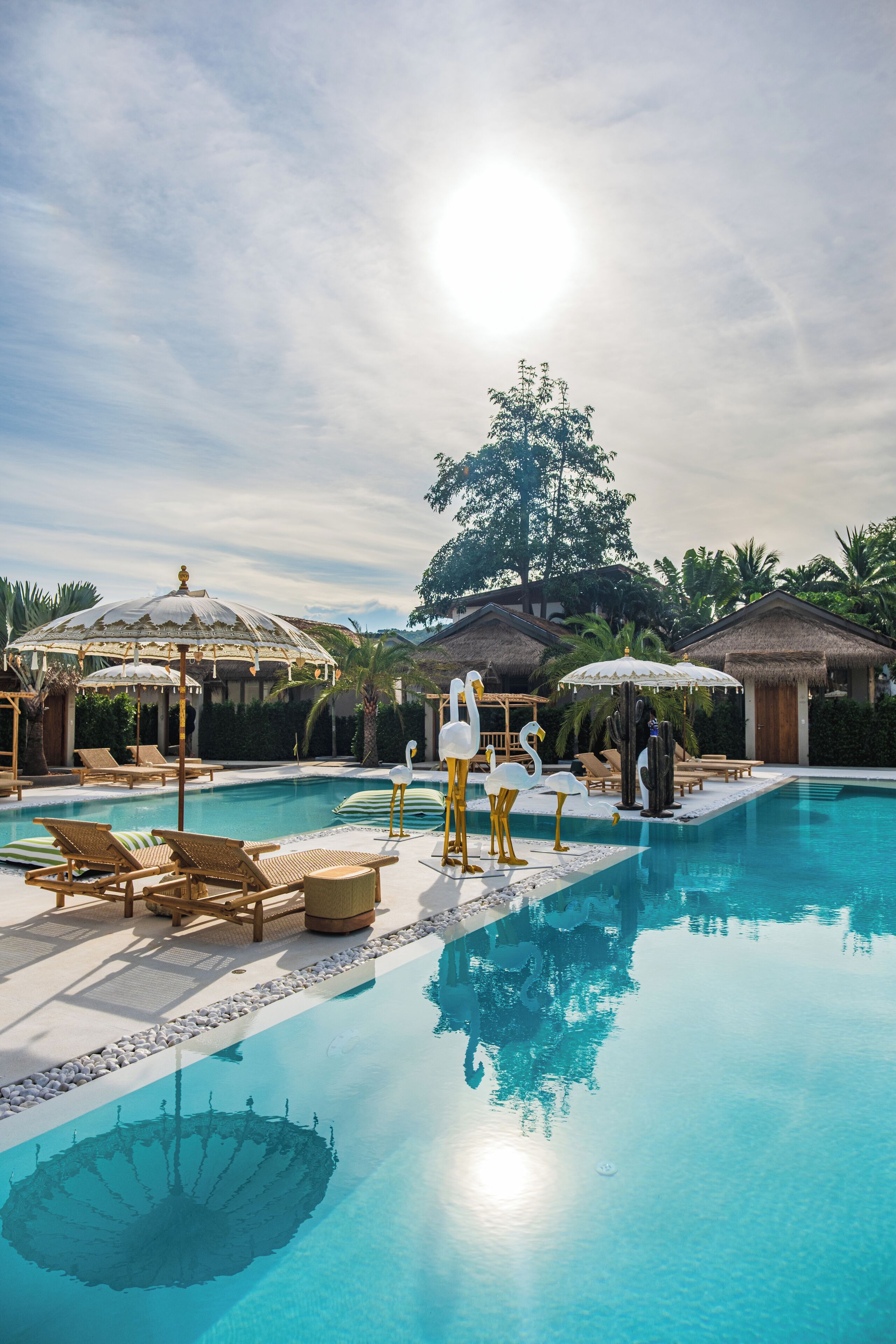 A pool area with lounge chairs, umbrellas, and decorative swans.