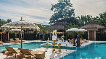 A pool area with lounge chairs, umbrellas, and decorative swans.