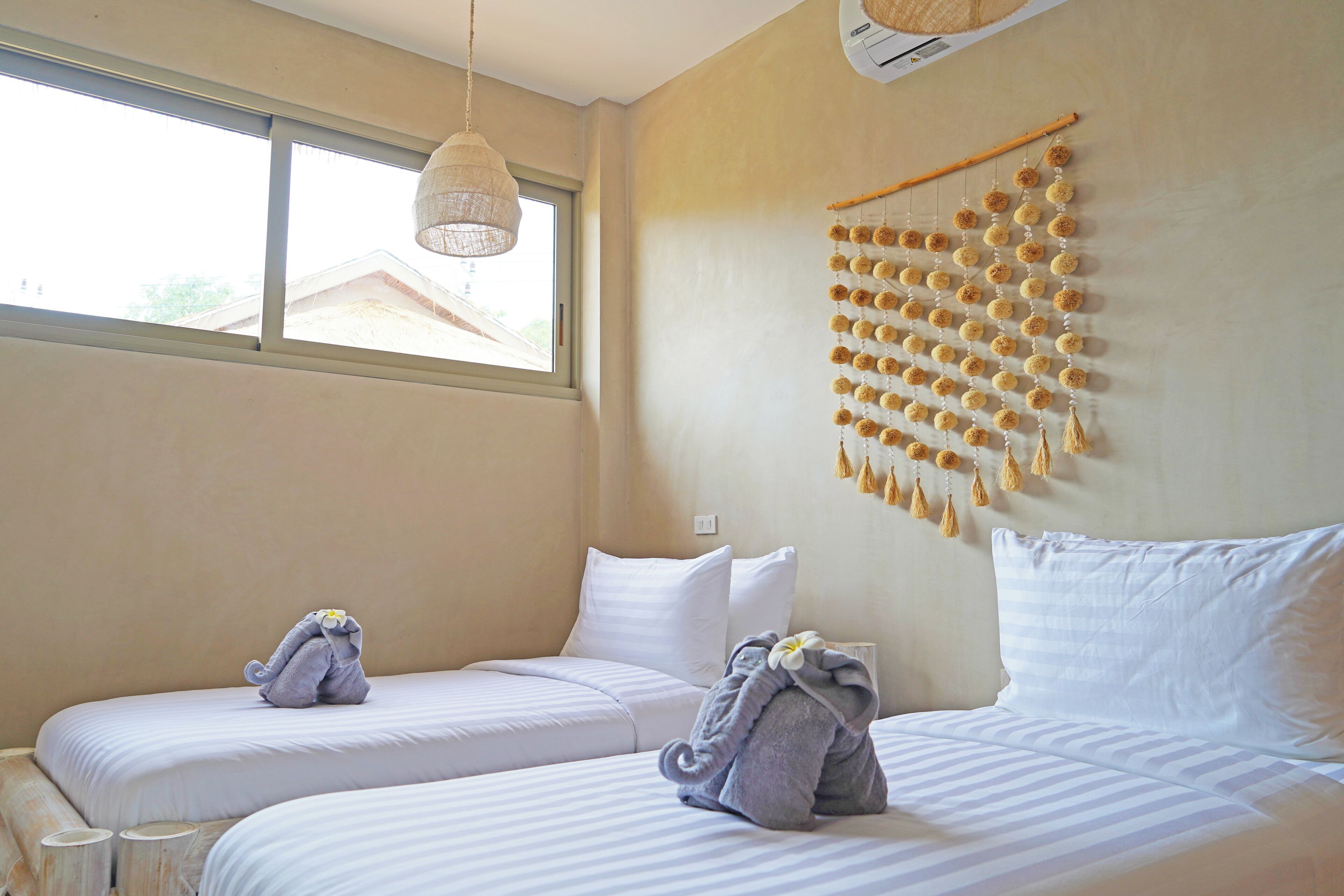 A hotel room with two beds, a large window, and a wall decoration.