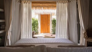 Une chambre à coucher avec un lit, des rideaux, une porte en bois et une vue sur un jardin.