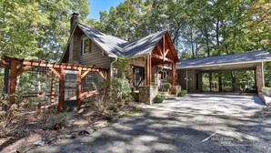 A rustic cabin with a stone foundation, wooden beams, and a covered porch. - Lake Reflections | Sleeps 6 | No Pet Fee | lakefront w/dock | paved | Hot Tub (Hiawassee)