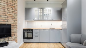 Cocina compacta con armarios grises, horno negro y encimera de madera.