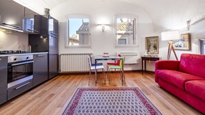 A compact living space with a kitchenette, dining area, and a red sofa.