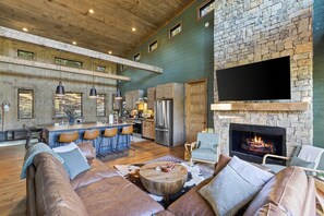 A spacious living area with a stone fireplace, leather sofas, and a bar area. - 5 min to Downtown Blue Ridge with Sunrise Views -Sauna -Hot Tub -Firepit (Blue Ridge)