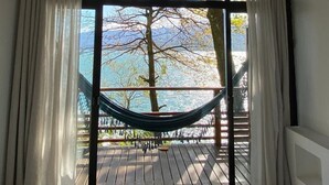A room with a large window, a hammock, and a ceiling fan.
