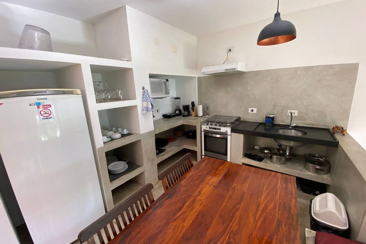 A compact kitchen with a built-in refrigerator, microwave, stove, and sink.
