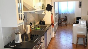 A compact kitchen with white cabinets, a black countertop, and a wooden chair. - 15 min from Neuss main station. Apartment for rent in quiet residential street. (Neuss)