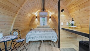 Tunnelmallinen, puupaneelilla verhoiltu huone, jossa on sänky, pieni pöytä tuoleineen ja baarialue.
