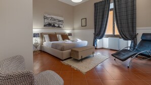 Un dormitorio con cama, una silla, un tapete y una lámpara de pared.