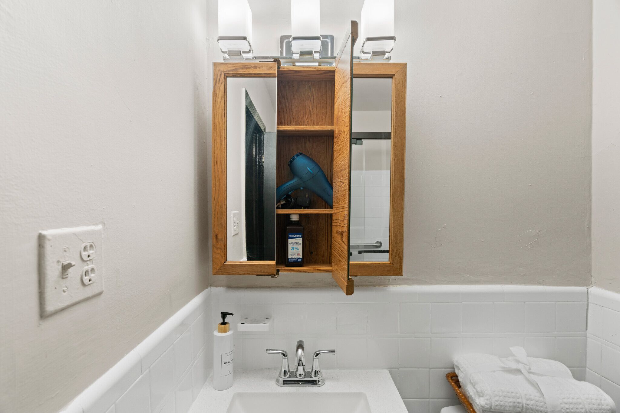 A bathroom with a wooden medicine cabinet, a white sink, and a bathtub.
