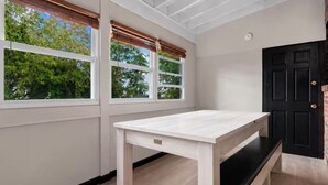 A room with a white table, two windows with blinds, a black door, and a visible clock. - Capitol Hill King Bed Suite+Free Parking+Private Lounge (Washington)