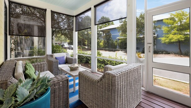 Un solárium con mobiliario de mimbre, ventanas amplias y vistas al exterior.