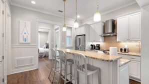 Una cocina moderna con armarios blancos, encimera de granito y campana extractora de acero inoxidable.