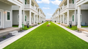 A row of white buildings with balconies and a green lawn in the center.