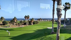 Ein Golfplatz mit freiem Blick auf das Meer und Palmen.