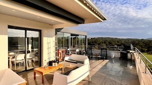 Un patio moderno al aire libre con comedor, asientos y vistas al paisaje.