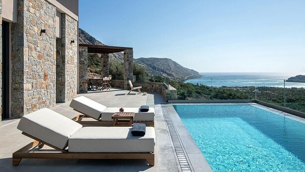 Un área moderna junto a la piscina con sillones de descanso y vistas al mar.