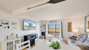 Un soggiorno moderno con zona pranzo, televisione e vista sulla spiaggia.