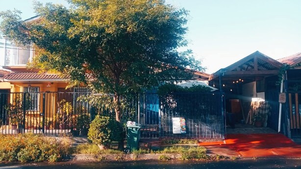 Un quartier résidentiel avec une cour clôturée, un arbre et un bâtiment doté d’un toit rouge.