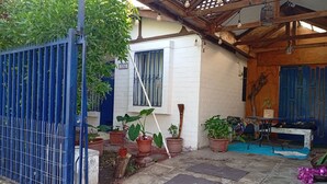 Une cour avec une porte bleue, des plantes en pot, un banc et une table sur laquelle est posée une plante.