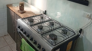 Une cuisine équipée d’une cuisinière à gaz, de placards et d’une fenêtre.