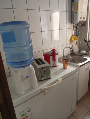 Eine Küche mit Wasserspender, Toaster, Spüle und Geschirrgestell.