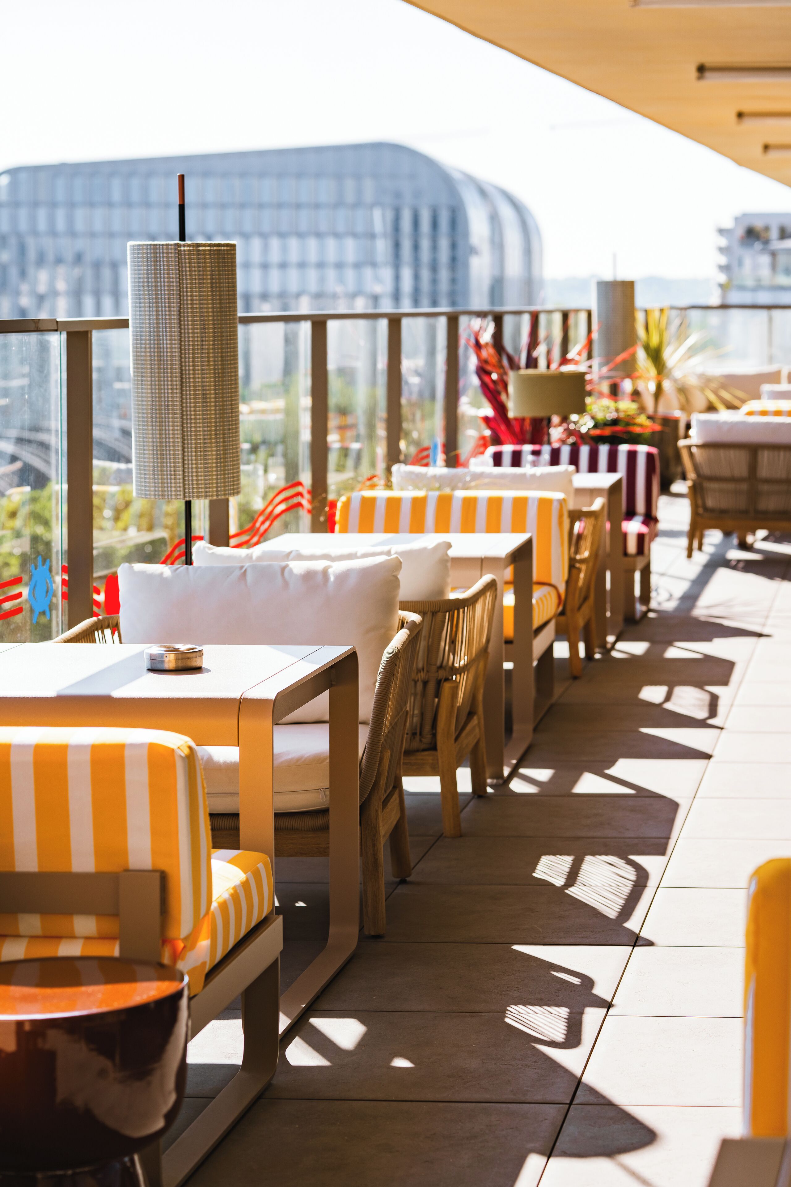 A rooftop terrace with outdoor seating, including striped and wicker chairs, and tables with umbrellas.