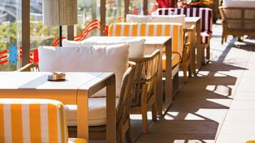 A rooftop terrace with outdoor seating, including striped and wicker chairs, and tables with umbrellas.