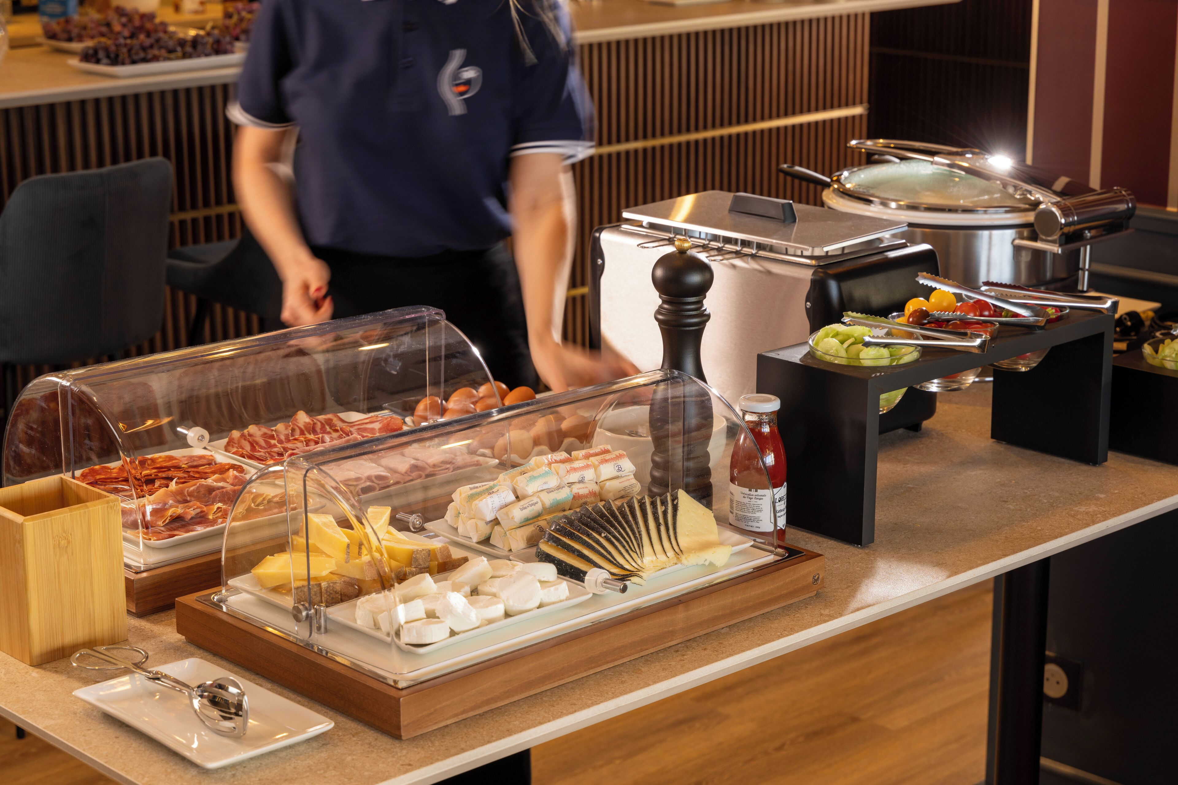 A buffet with various food items including meats, cheeses, and fruits.