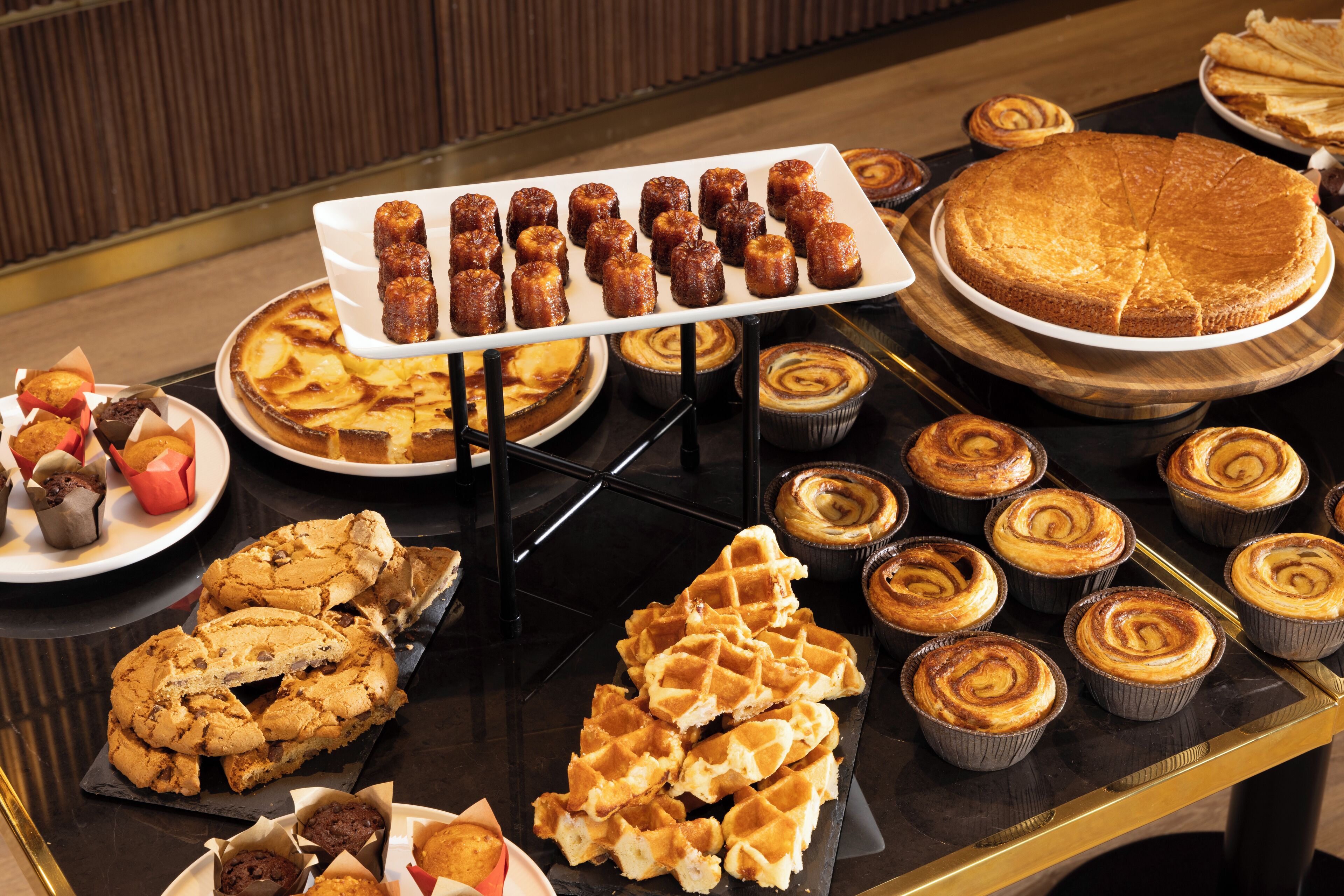 Un tavolo da buffet con diversi prodotti da forno, tra cui torte, pasticcini e biscotti.