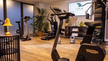 Un gimnasio de hotel con varios equipos de ejercicio, incluyendo cintas de correr y una bicicleta estática.