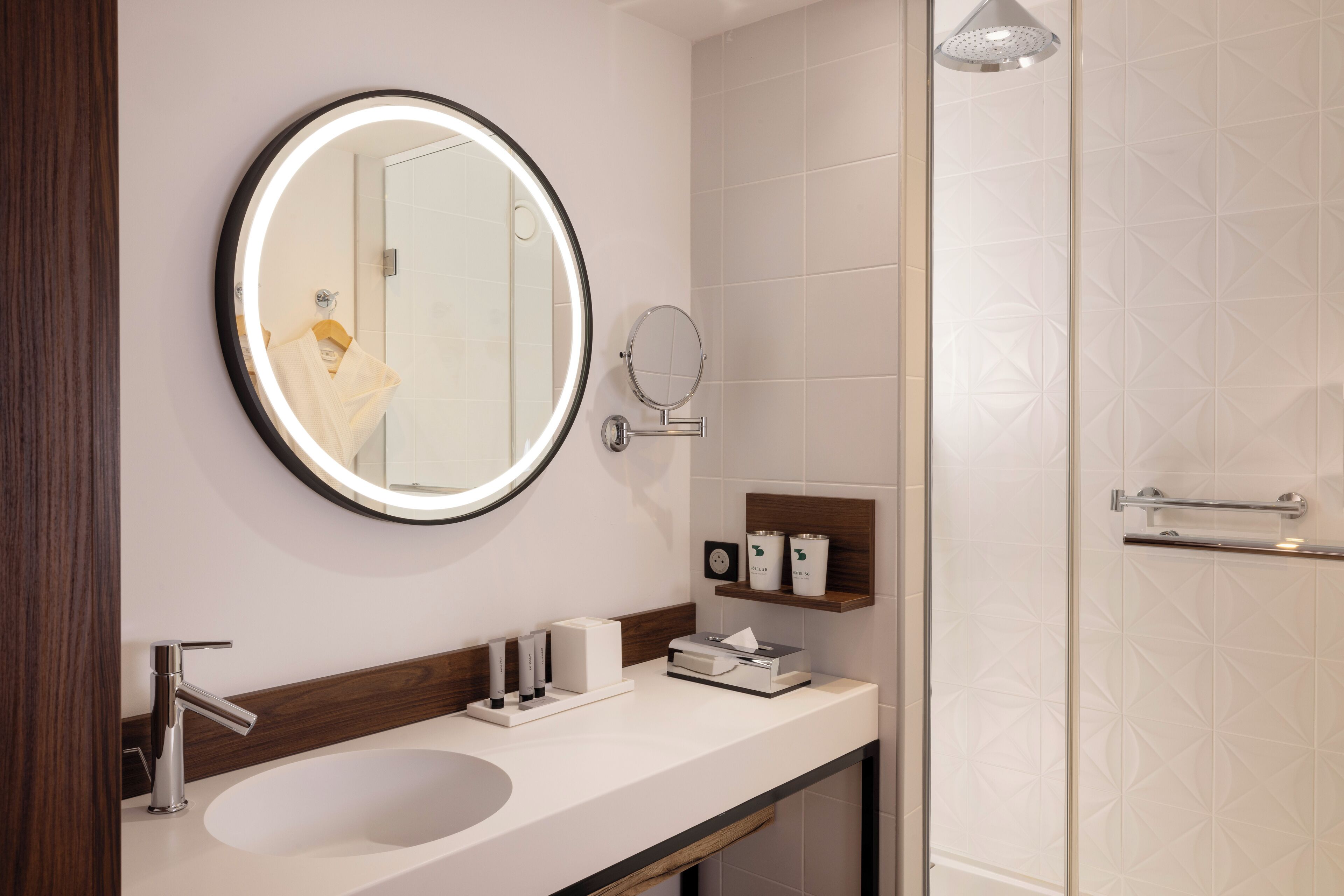 A modern bathroom with a round mirror, a sink, and a shower area.