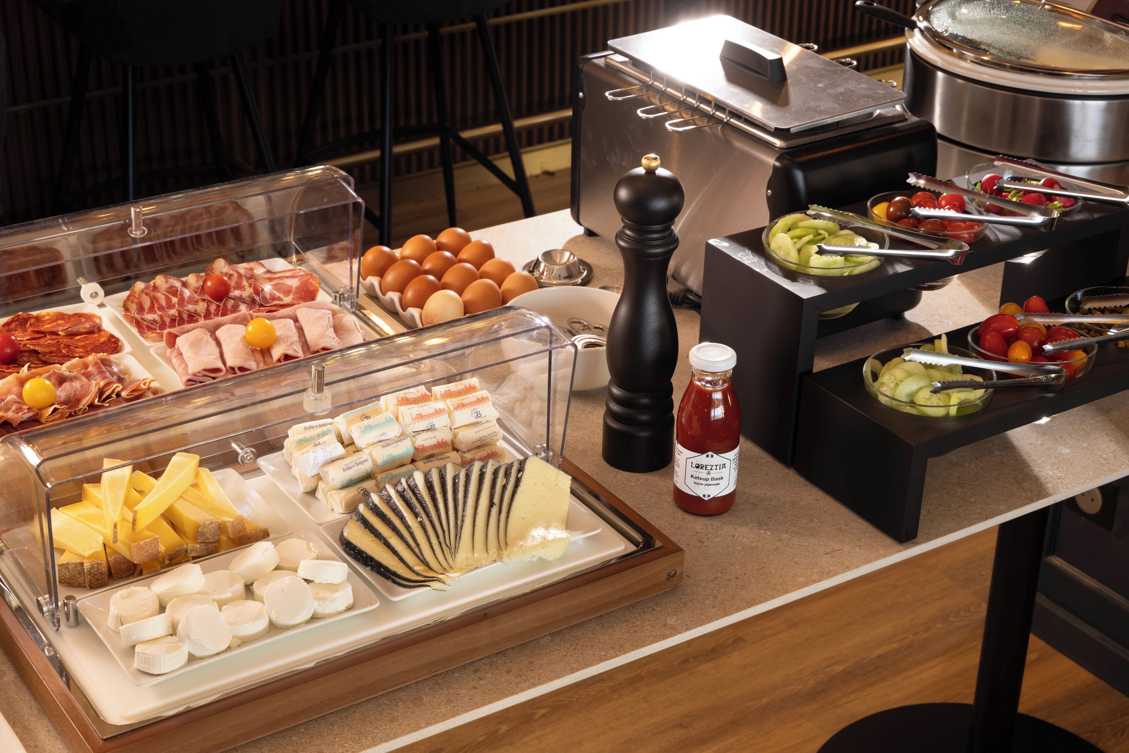 A buffet with various food items including meats, cheeses, and vegetables.