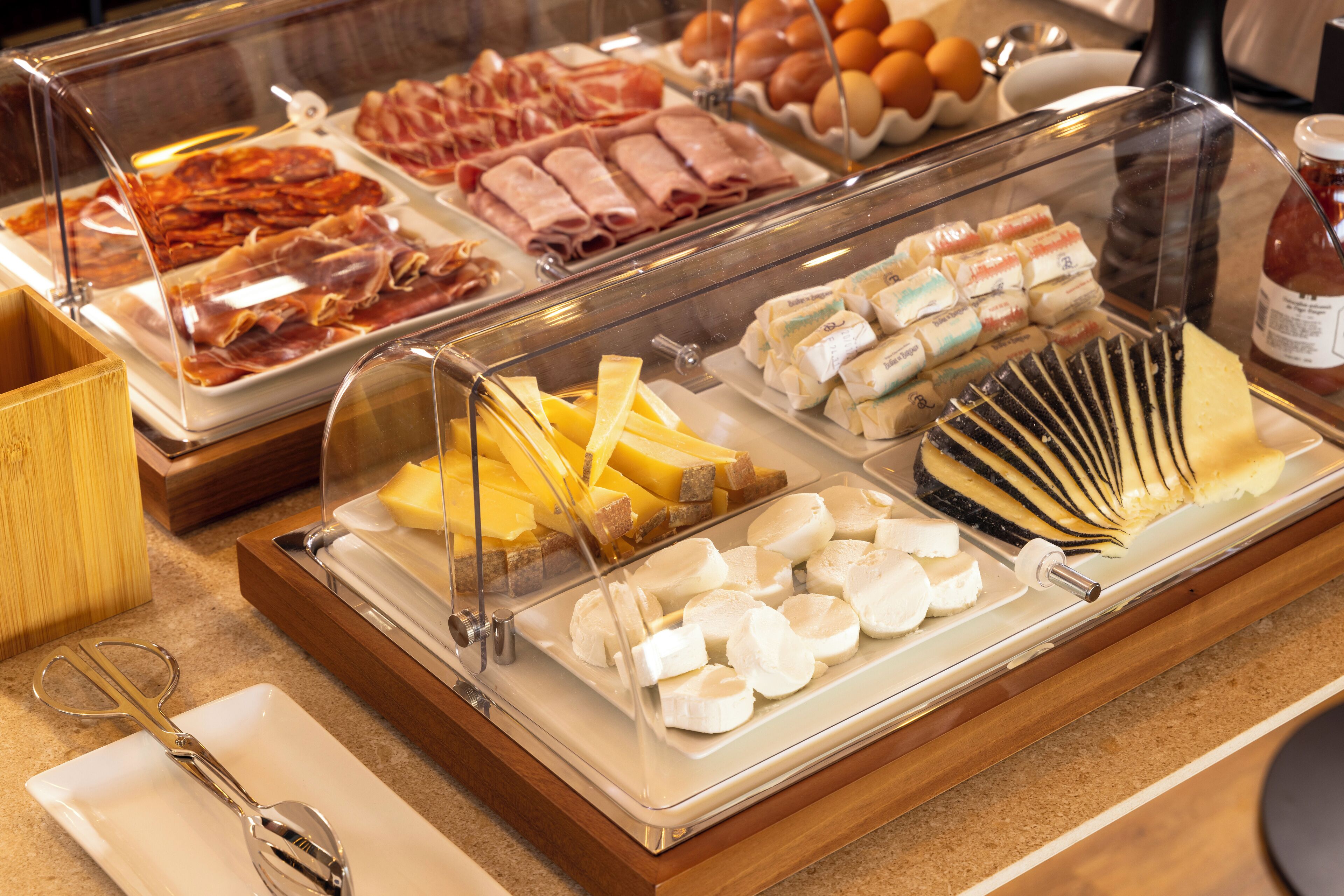 Un bufé de desayuno con diversas carnes, quesos y frutas.